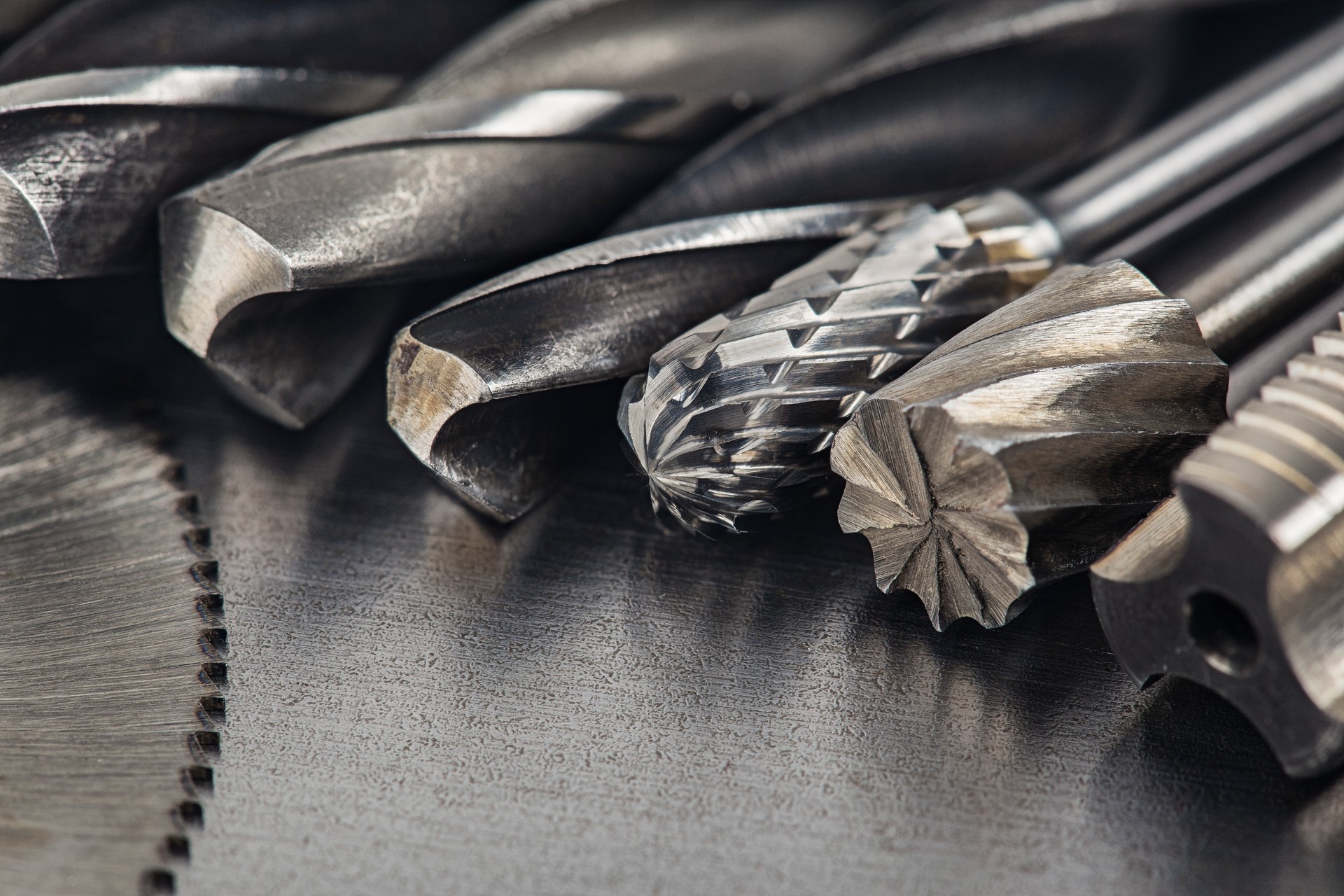 set of different drill bits,thread tap and mill cutters with caliper ruler on steel plate background. Locksmithing deal.